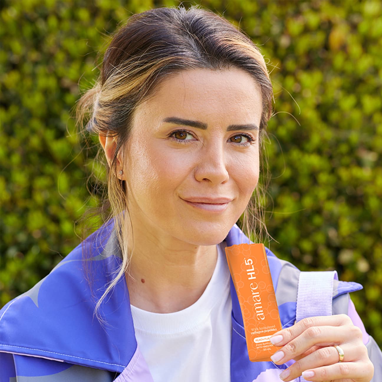 Gebruiker met Amare HL5 vloeibaar collageen sachet — collageen supplement voor huid, haar en nagels